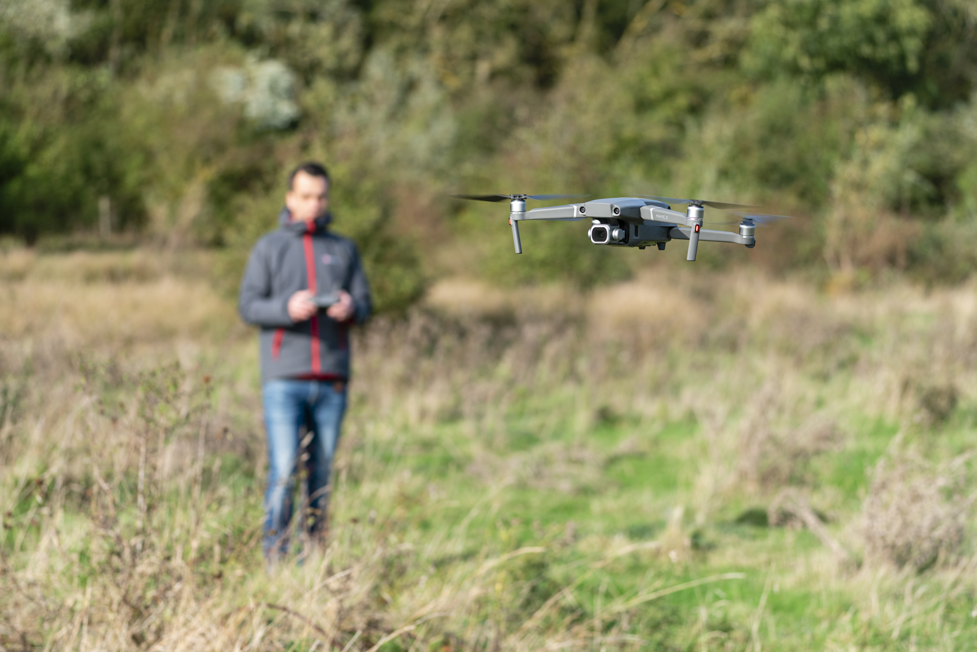 A man flying a DJI drone in a field