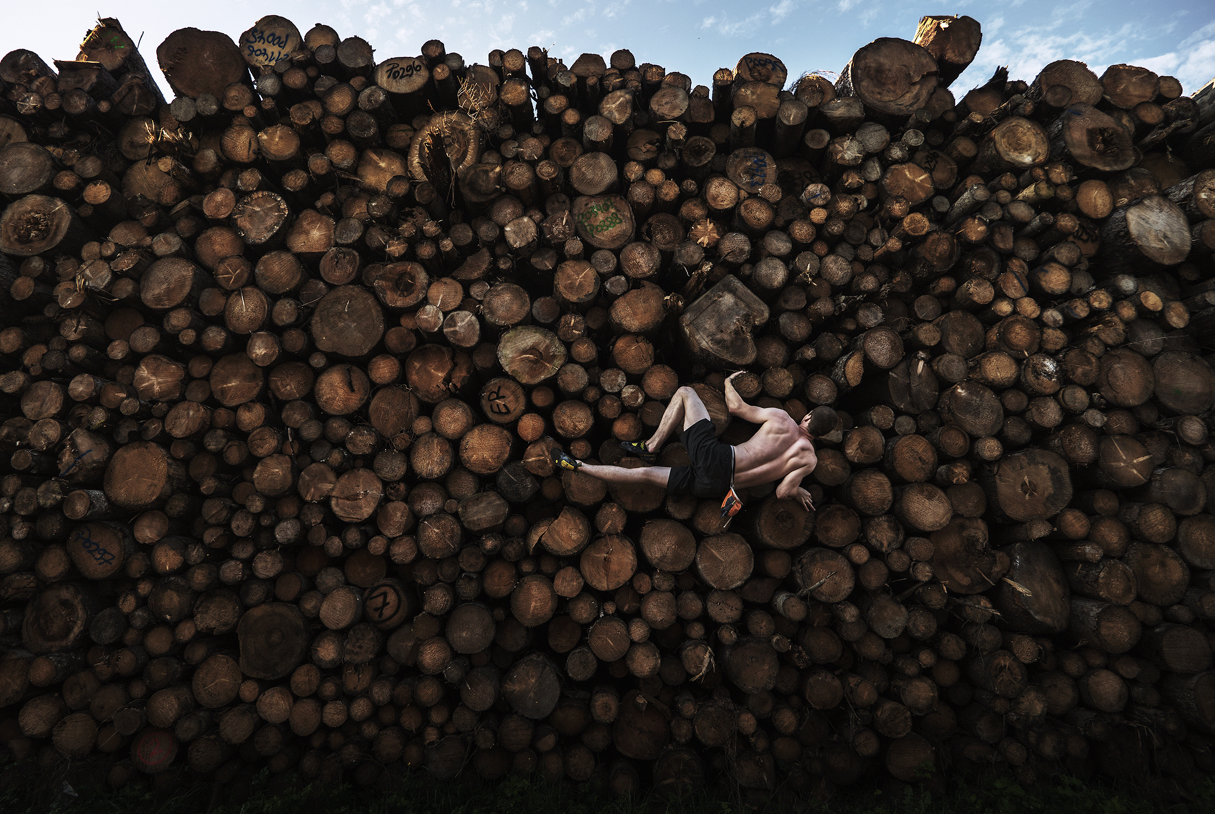 A man bouldering on a log pile