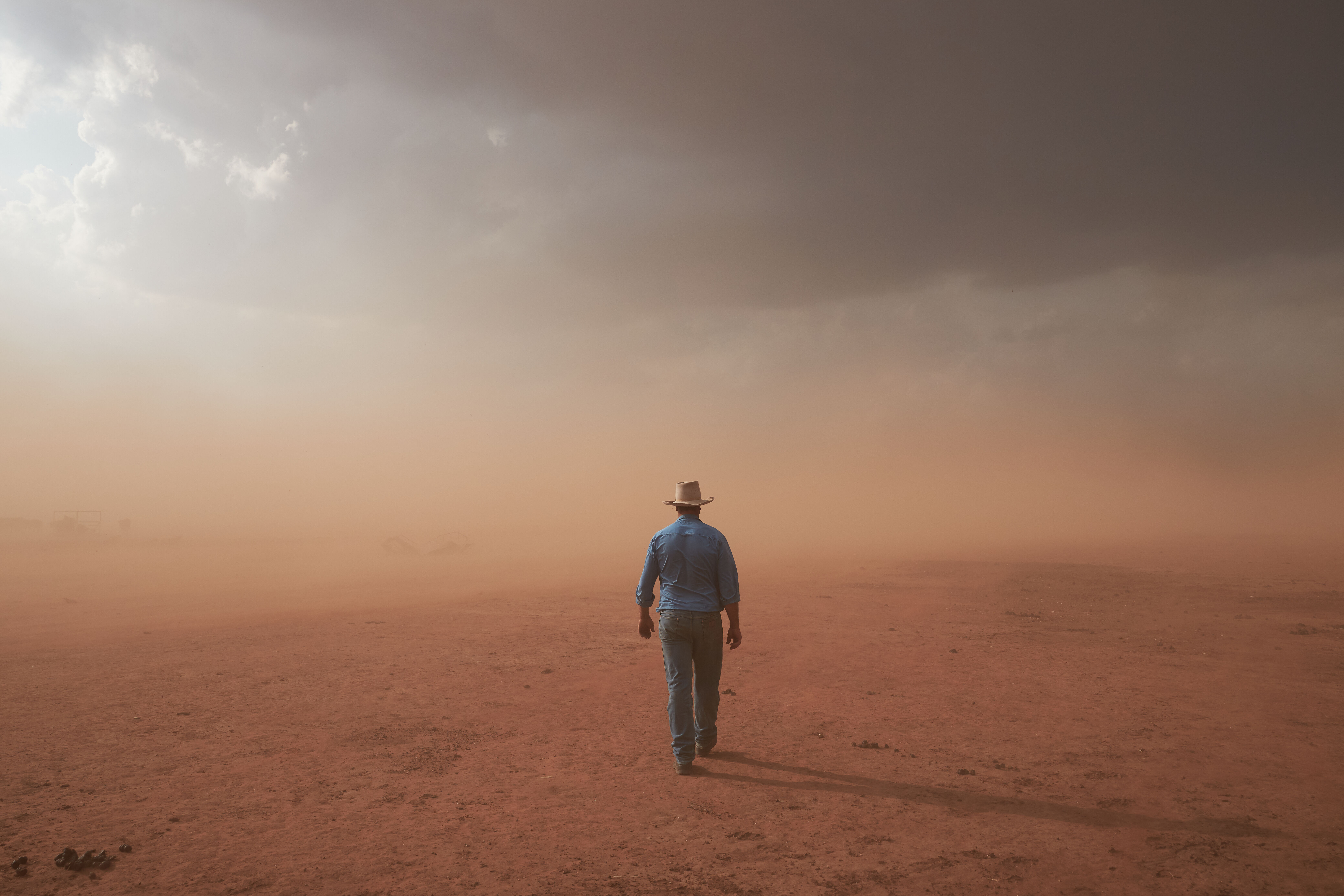 A farmer walking into a barren landscape during drought