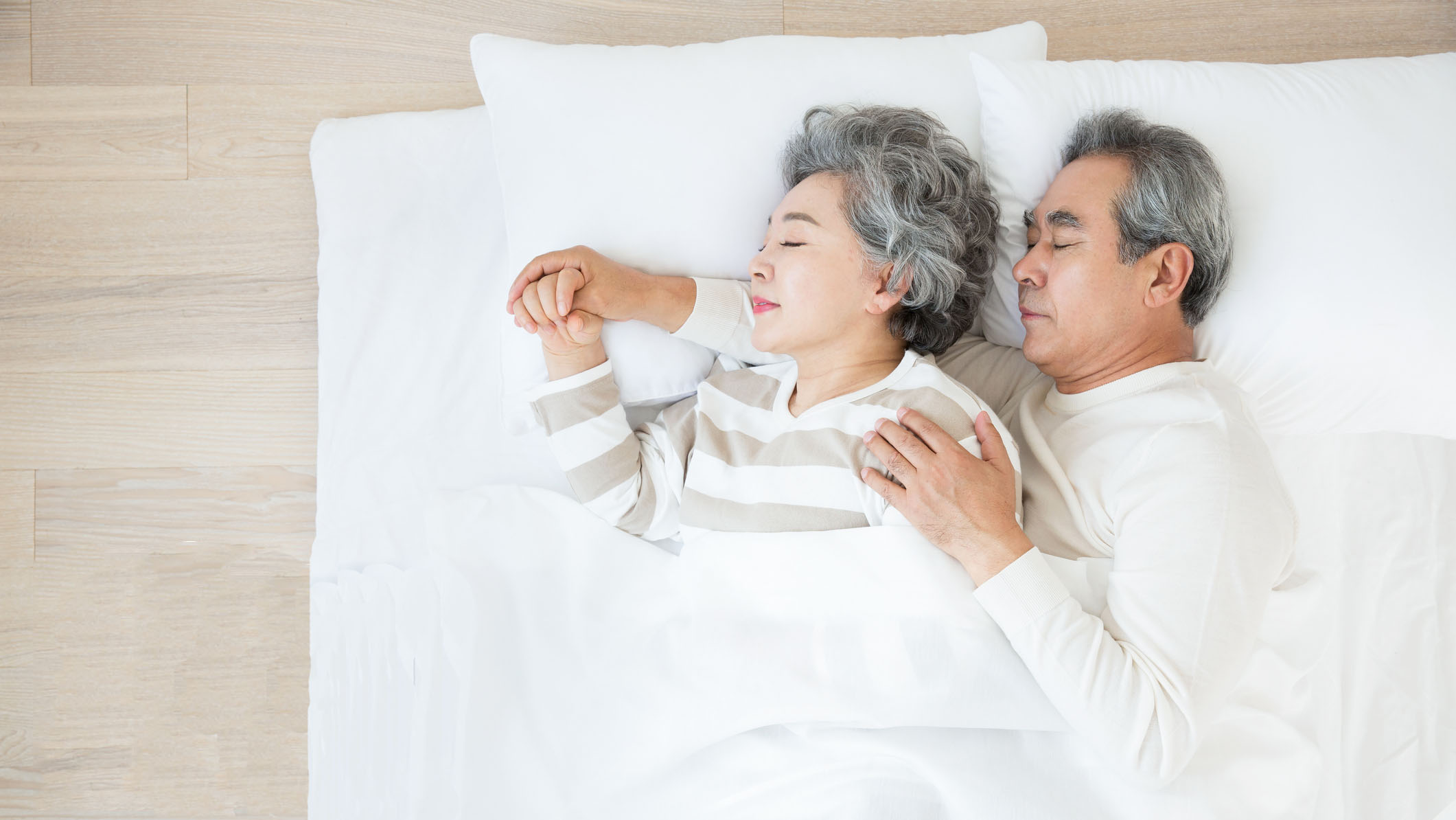 An elderly couple cuddle while sleeping on a comfy foam mattress